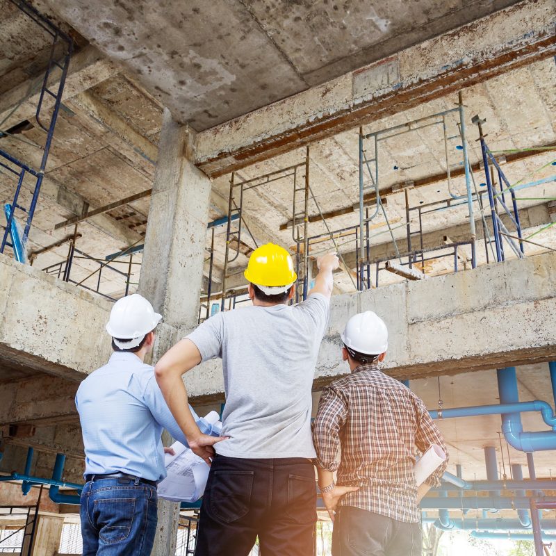 Engineer, foreman and worker discussing in building construction site
